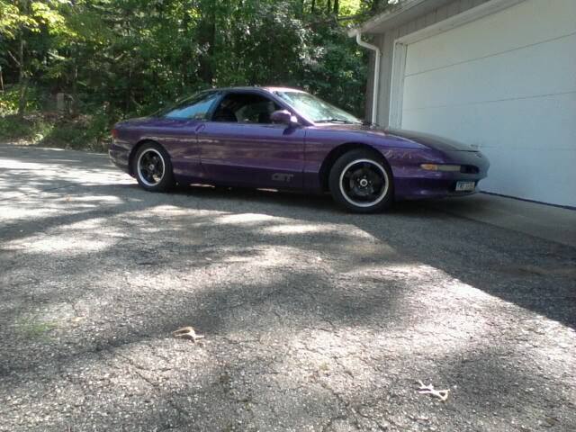 Purple 1995 Ford Probe parked in front of a garage.