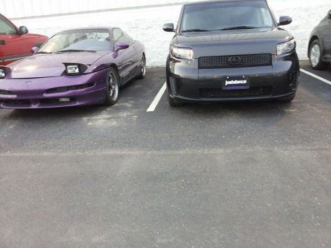 1995 Ford Probe - A purple 1995 Ford Probe is parked next to a dark gray Scion xB in a parking lot.