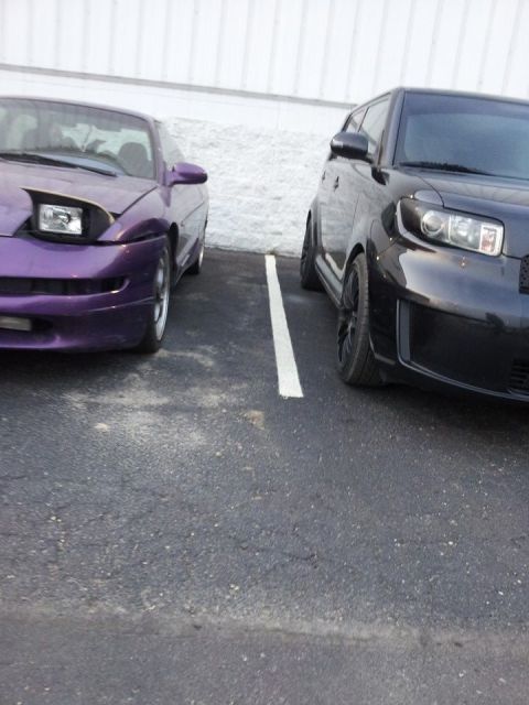 1995 Ford Probe - A purple 1995 Ford Probe is parked next to a black car in a parking lot. The purple car has its driver's side headlight exposed.