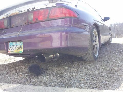 1995 Ford Probe - The rear driver's side of a purple 1995 Ford Probe is shown parked on a gravel surface. The car features a custom exhaust tip and an Ohio l…