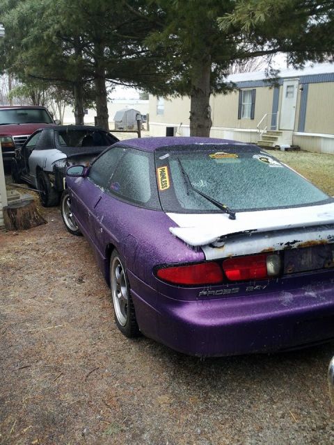 1995 Ford Probe - A purple Ford Probe is parked outside on a gravel surface, covered in ice. Another car, partially disassembled, is parked in front of it.