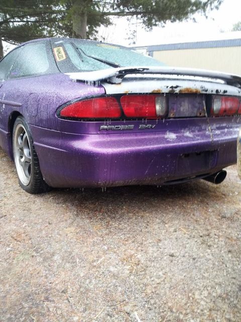1995 Ford Probe - The rear passenger side of a purple Ford Probe is shown covered in ice and water droplets. The car has a spoiler and the text "PROBE 24V" i…