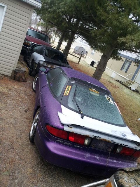 1995 Ford Probe - A purple 1995 Ford Probe is parked next to a red Ford F-150 pickup truck. The Probe has a white spoiler and a white stripe on the rear.
