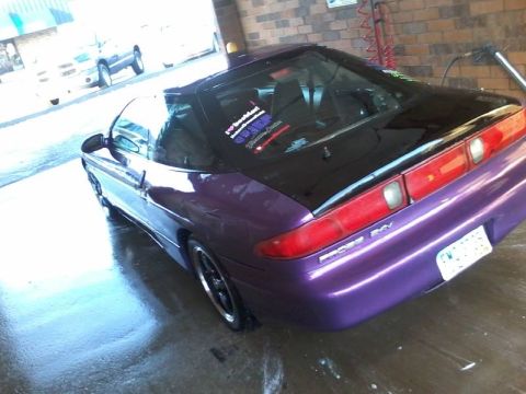 1995 Ford Probe - A purple 1995 Ford Probe is parked on a wet floor, possibly after a wash. The car has a black roof and a custom license plate.