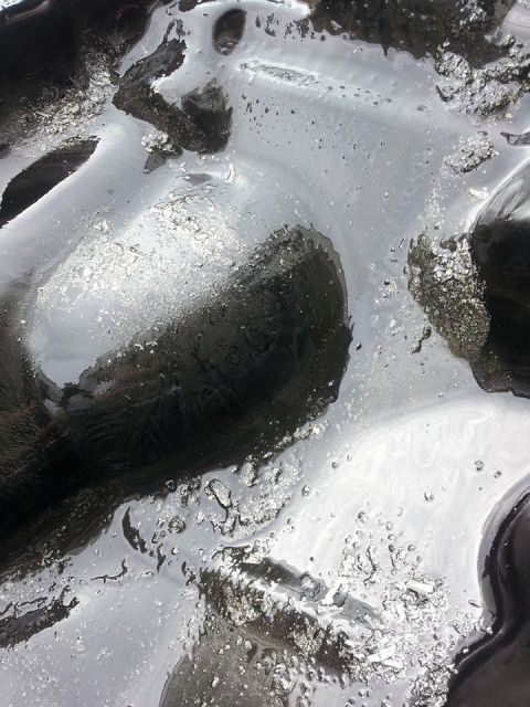 1995 Ford Probe - A close-up abstract shot of what appears to be a dark, viscous liquid with reflective qualities and small bubbles.