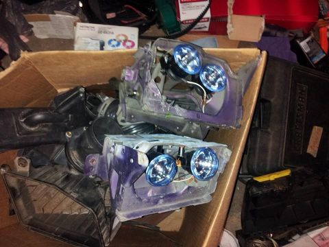 1995 Ford Probe - Two disassembled car headlight assemblies with blue bulbs are piled in a cardboard box with other car parts. A black Craftsman toolbox is v…