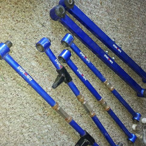 1995 Ford Probe - A set of bright blue adjustable control arms with gold hardware are laid out on a carpeted surface. White text reading " Megan " is visible…