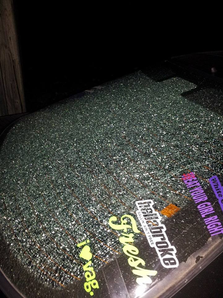 Shattered rear window of a 1995 Ford Probe with glittery stickers.