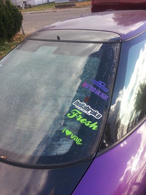 1995 Ford Probe - The rear window of a purple 1995 Ford Probe, nicknamed "Starscream," is shown with several stickers and a cracked windshield.