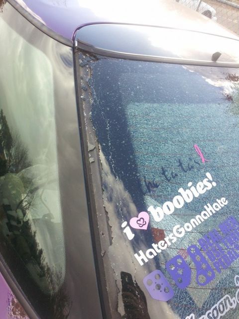 1995 Ford Probe - A close-up view of a cracked rear window on a purple car, adorned with several stickers. The stickers include text like "i ❤️ boobies!" and…