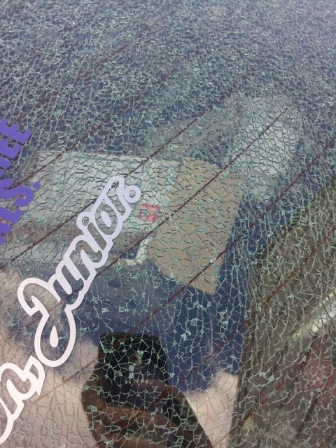 1995 Ford Probe - A close-up of a cracked rear window on a vehicle, featuring white text that reads "Junior" and a partial purple decal. The defroster lines…
