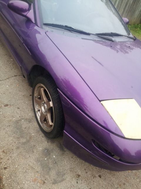 1995 Ford Probe - A close-up, low-angle shot of the front fender and wheel of a custom purple 1995 Ford Probe. The vehicle features a bronze five-spoke after…