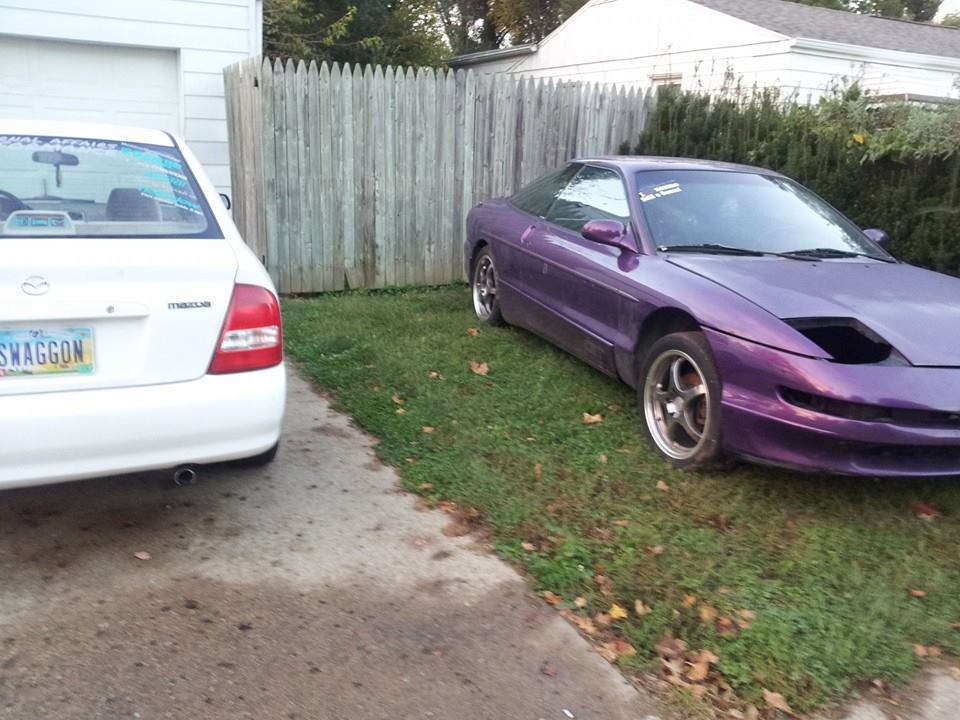 Purple 1995 Ford Probe with headlights down, parked next to a white Mazda.