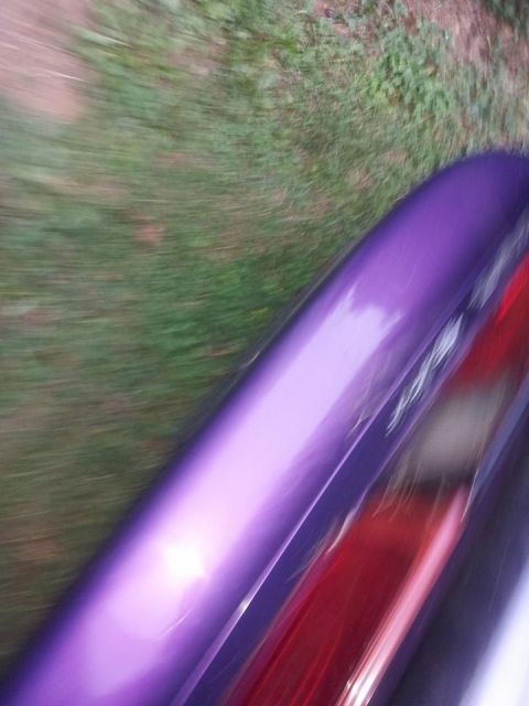 1995 Ford Probe - A close-up, blurred shot of the rear passenger side of a purple vehicle, showing the fender and part of the taillight. The vehicle is seen…