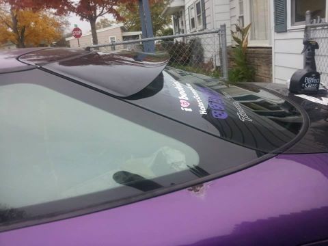 1995 Ford Probe - The rear passenger side of a purple 1995 Ford Probe is shown, with a spoiler on the roof and several stickers on the rear window. A bottle…