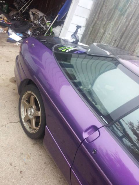 1995 Ford Probe - A purple 1995 Ford Probe is parked in a garage with various car parts and tools visible in the background. The car's exterior features a sp…