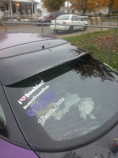 1995 Ford Probe - The rear of a dark colored car is shown with several stickers on the back window. The stickers read "i❤️boobies!", "HatersGonnaHate", and "…