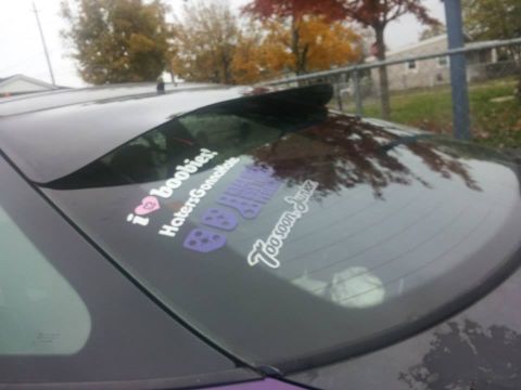 1995 Ford Probe - The rear window of a dark-colored car features several stickers. Visible text includes "i❤boobies! HatersGonnaHate" and "Too Soon Junior".