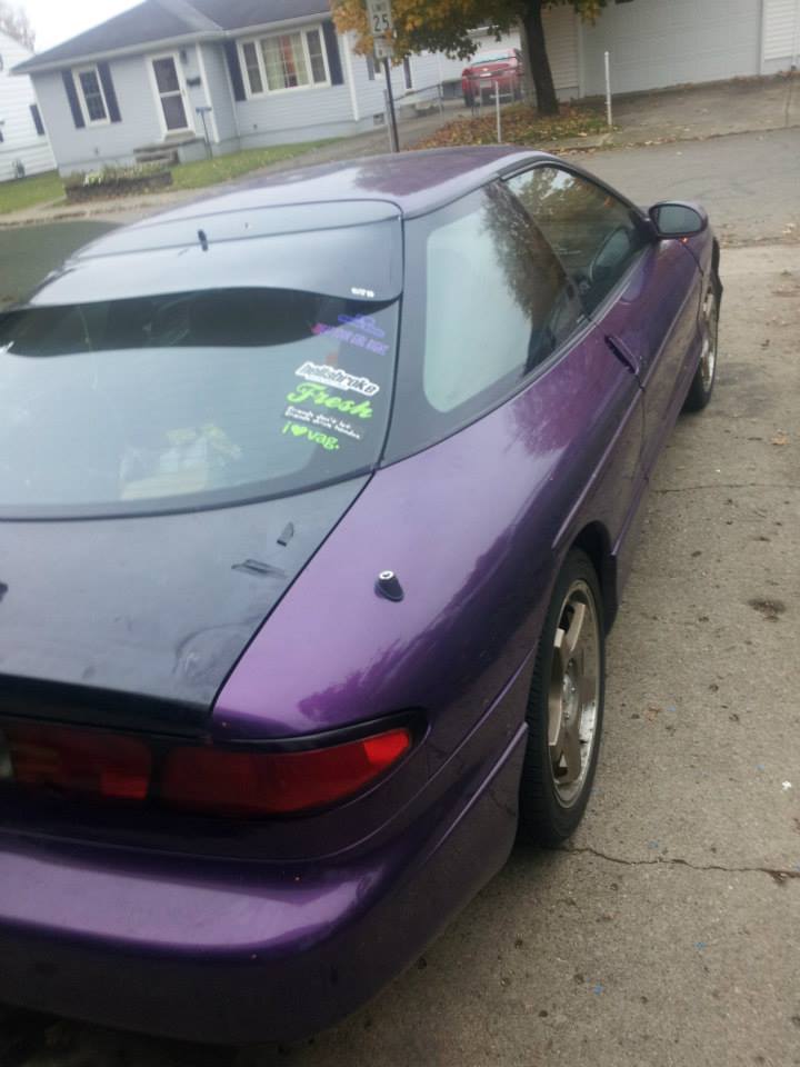 Purple 1995 Ford Probe rear driver's side quarter panel with stickers on the window.