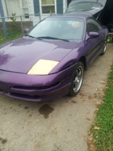 1995 Ford Probe - A purple 1995 Ford Probe is parked on a concrete driveway with the trunk open. The car has a light-colored square on the hood, possibly a h…