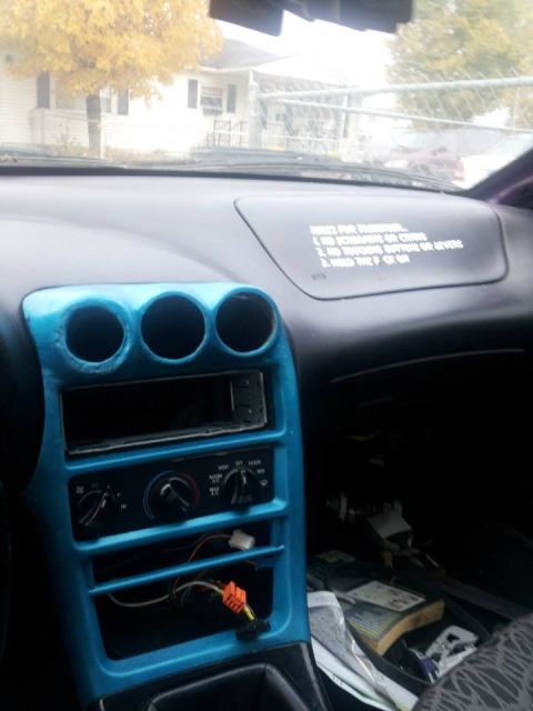 1995 Ford Probe - The interior of a car shows a bright blue dashboard with a car stereo and climate controls. A sticker with rules is visible on the dashboar…
