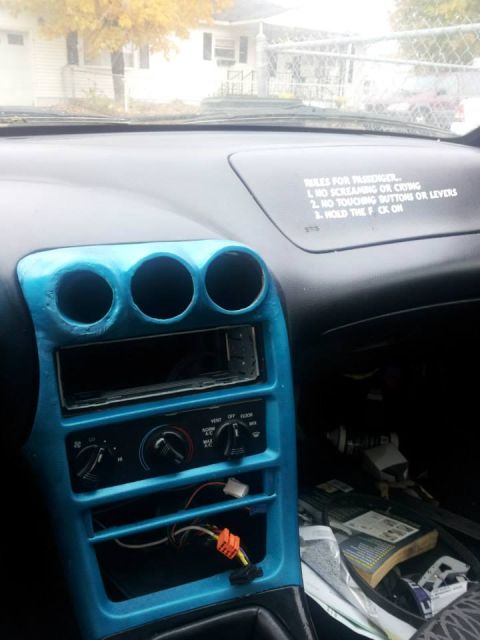 1995 Ford Probe - Interior view of a car's dashboard with a blue-painted center console, showing the radio area, climate controls, and a sticker with rules f…