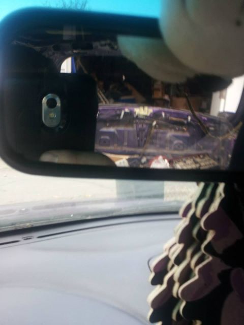1995 Ford Probe - The reflection in the rearview mirror shows the interior of a vehicle with a purple car or car part visible in the background. A fuzzy, lig…