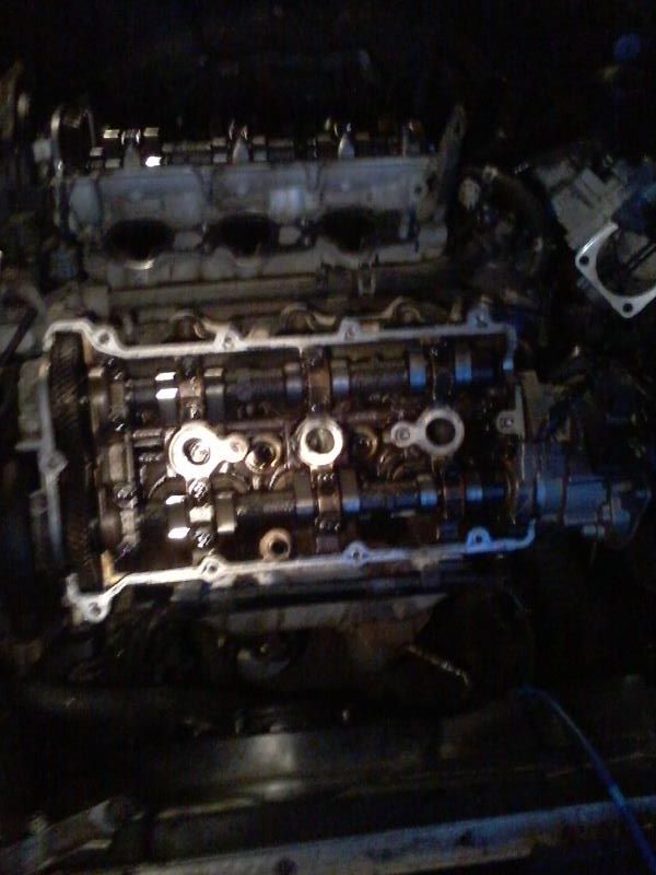 Disassembled engine with camshafts and valve train exposed.