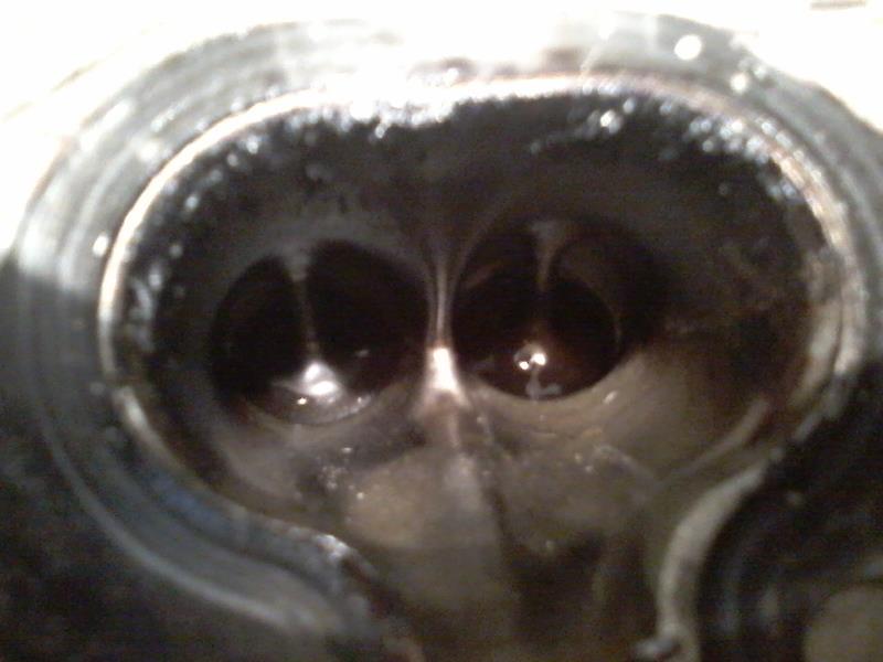 Close-up of cylinder head combustion chambers with carbon buildup and two intake valves.