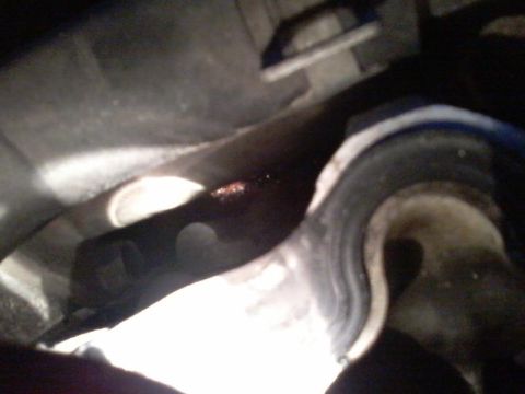 1995 Ford Probe - A close-up view of a dark, possibly greasy, mechanical component, possibly part of a vehicle's undercarriage. A small amount of red fluid i…