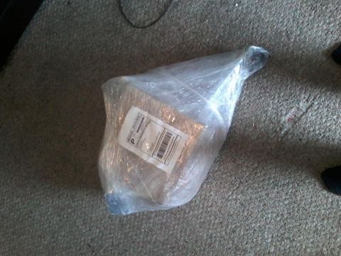 1995 Ford Probe - A package wrapped in clear plastic wrap sits on a carpeted floor. A shipping label is visible on the package.