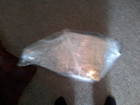 1995 Ford Probe - A clear plastic-wrapped object sits on a carpeted surface. The object is rectangular and appears to contain some sort of material.