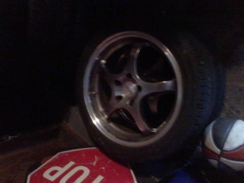 1995 Ford Probe - A close-up view of a car wheel and tire is shown. A red stop sign with the word "UP" visible is in the foreground.