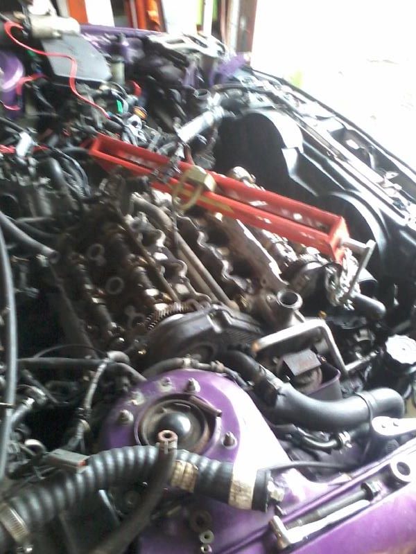 Engine bay of a purple 1995 Ford Probe with red engine hoist.