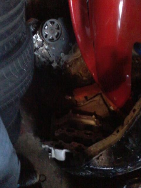 1995 Ford Probe - A close-up view of a vehicle's engine compartment, showing a pulley system and part of a red body panel. The area appears to be cluttered w…