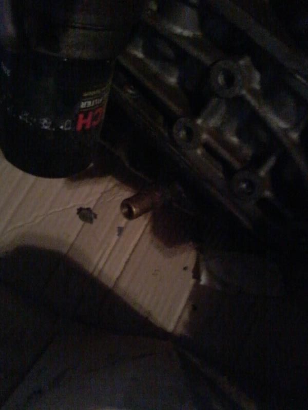 Black oil filter and brass fitting on a dark engine block, workshop setting