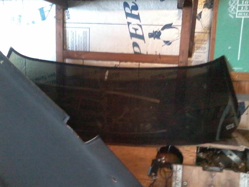 Curved dark windshield laid flat in front of building materials.