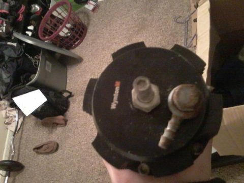 1995 Ford Probe - A close-up view of a black round automotive part with "Wynton M" visible on its surface. The part has two threaded fittings, one hexagonal…