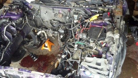 1995 Ford Probe - The engine bay of a purple 1995 Ford Probe is shown with the engine partially disassembled. Various tools and automotive parts are scattere…
