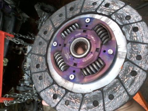1995 Ford Probe - A close-up, angled shot shows a clutch disc with a purple center hub and silver springs. The friction material on the disc is worn and show…