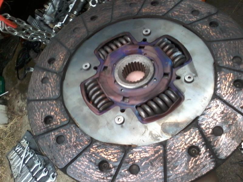 Car clutch disc with springs and splined hub, showing wear and heat discoloration.