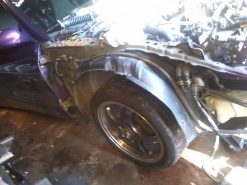 1995 Ford Probe - The front passenger side wheel well of a purple car is shown with the fender removed, revealing the engine bay and suspension components. T…
