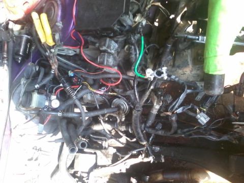 1995 Ford Probe - A close-up view of a car's engine bay with a complex arrangement of wires, hoses, and engine components. Tools are visible near the top lef…
