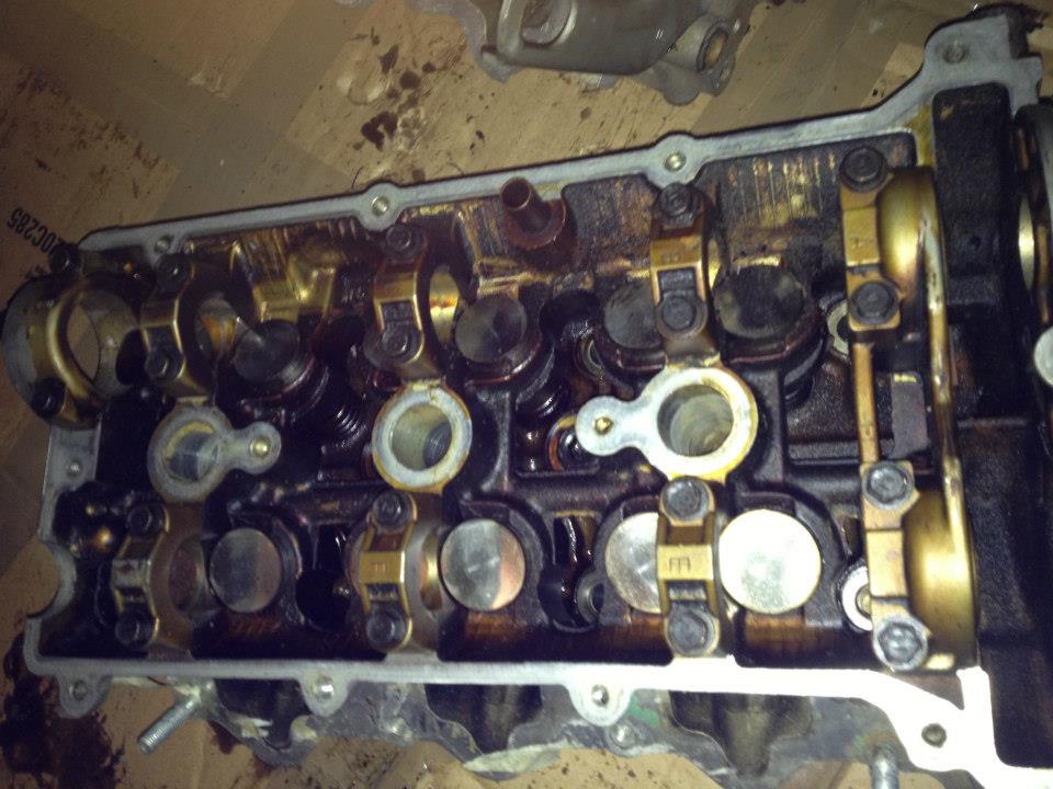 Overhead view of a dirty engine cylinder head with visible valve components.