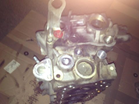 1995 Ford Probe - A close-up, slightly blurry, overhead view of a disassembled engine part, likely a cylinder head, with various bolts, ports, and metal comp…