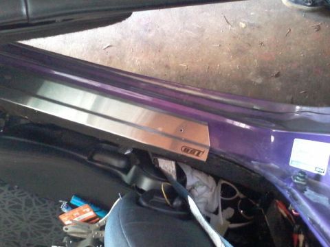 1995 Ford Probe - A close-up view of the interior door sill of a purple vehicle, featuring a brushed metal trim piece with a "GT" logo. Various items are vis…