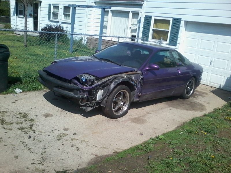 Purple Ford Probe with front end damage parked in driveway.
