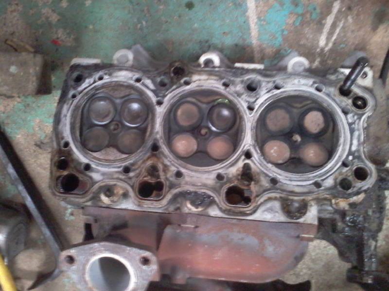 Cylinder head of a vehicle engine with valves visible, showing carbon buildup.