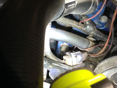 1979 Ford Bronco - A close-up view of engine components in a vehicle, including hoses, wires, and a sensor. A black ribbed hose dominates the left side of the…