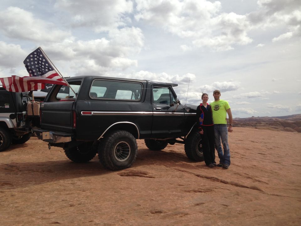 1979 Ford Bronco with American flag and a couple standing next to it in a desert landscape.